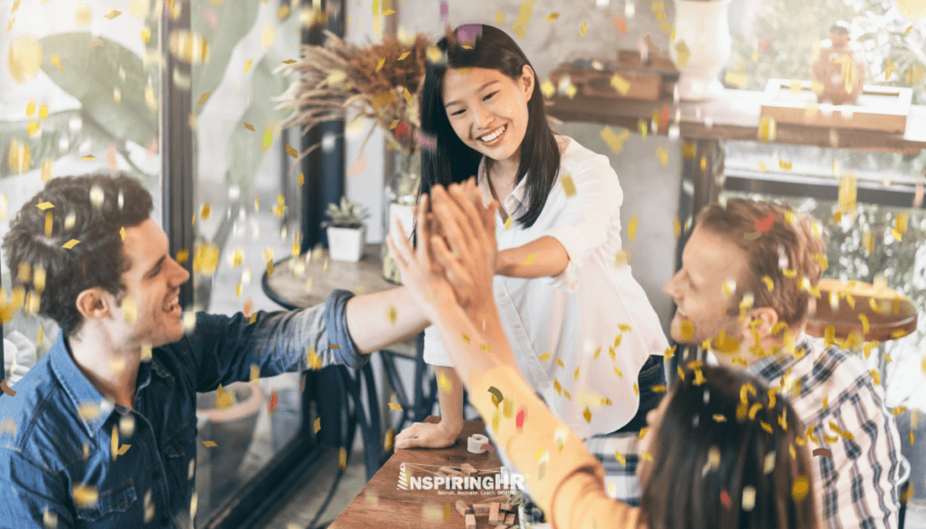 People celebrating a win and high-fiving each other indicating a healthy work culture.