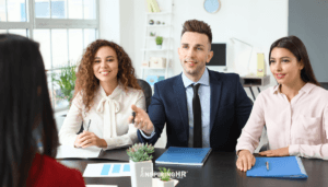 two women and a man in a business office participating in an interview or new hire onboarding session.